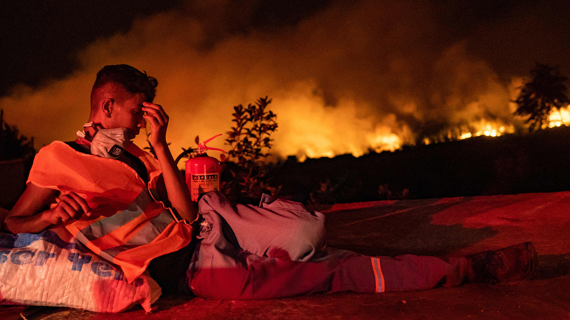 Ein freiwilliger Helfer sitzt vor einem Waldbrand in der Türkei. | AFP
