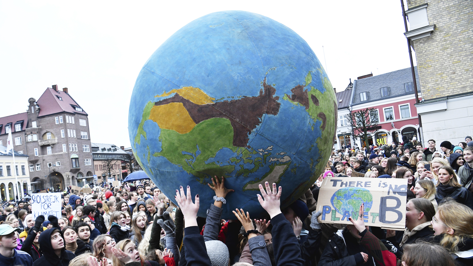 Schüler schubsen auf einer Klimademonstration eine Weltkugel hin und her.