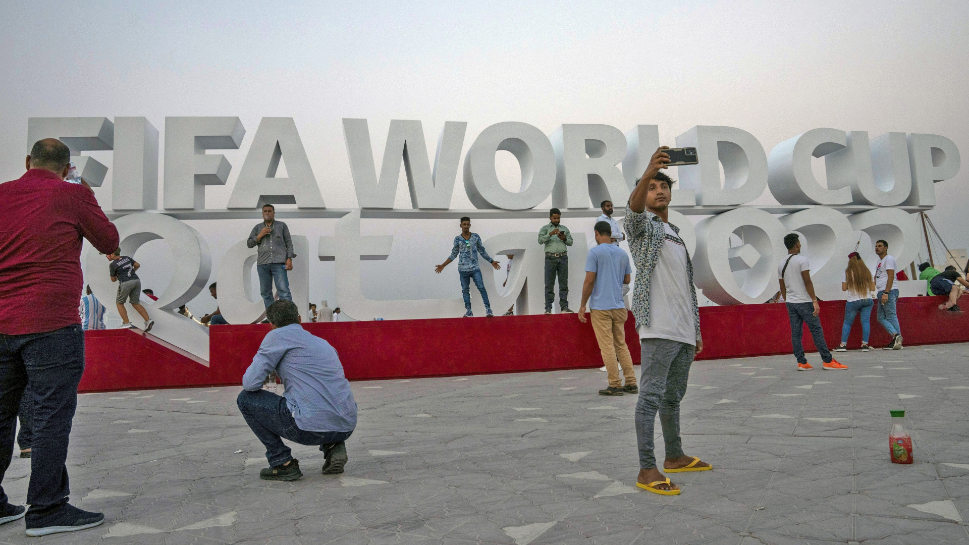 Menschen fotografieren auf der Corniche von Doha ein Schild mit dem Hinweis auf die FIFA Fussball-Weltmeisterschaft 2022. | dpa