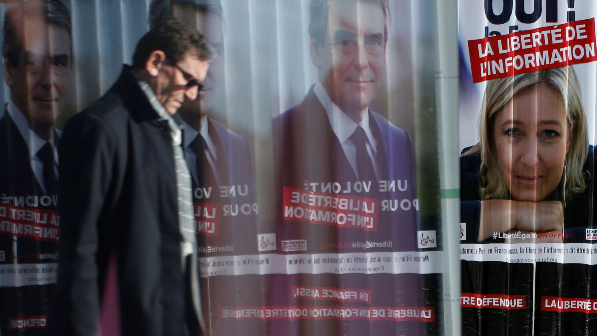Passant geht an Plakaten von Fillon und Le Pen vorbei.