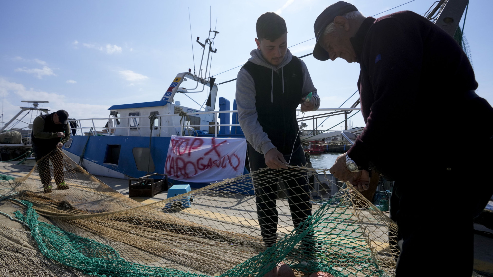 Fischer flicken Netze vor einem Fischerboot im Hafen von Fiumicino. | AP