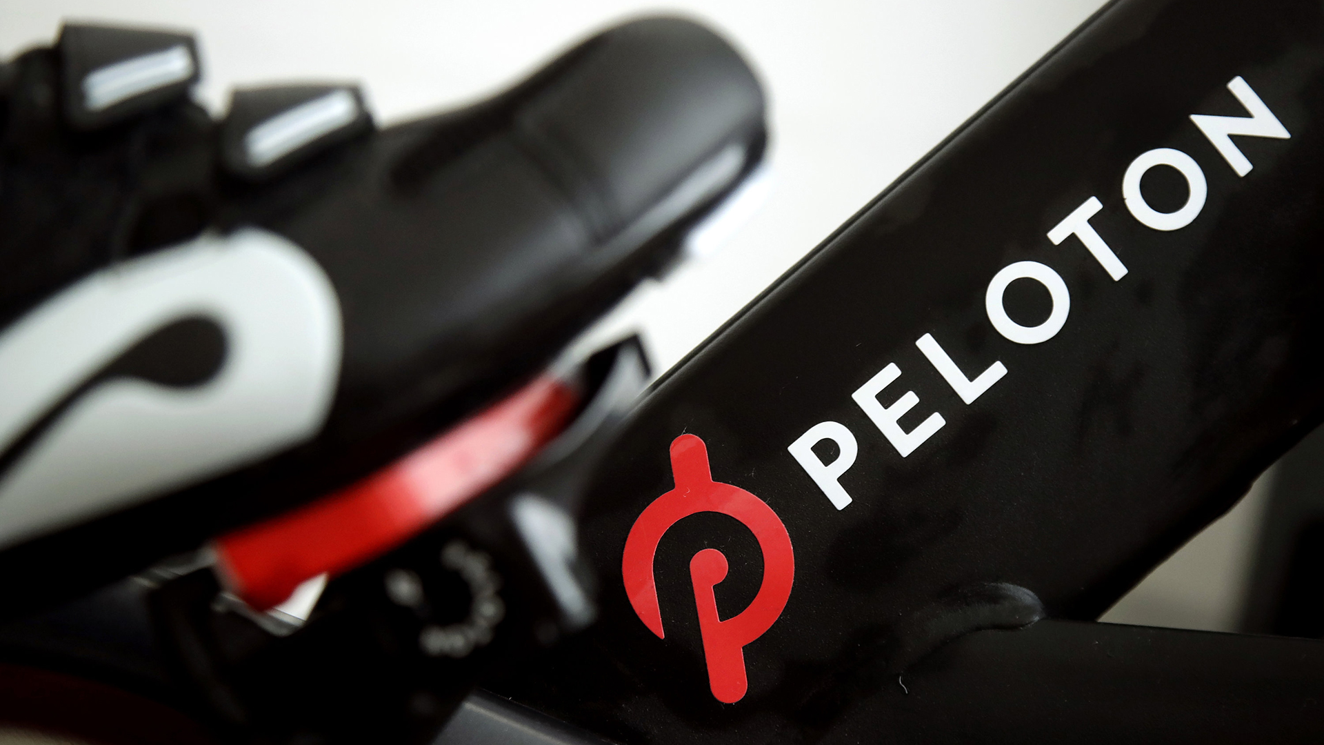 Ein Fuß steht auf dem Pedal eines stationären Trainingsrads der Firma Peloton. | AP