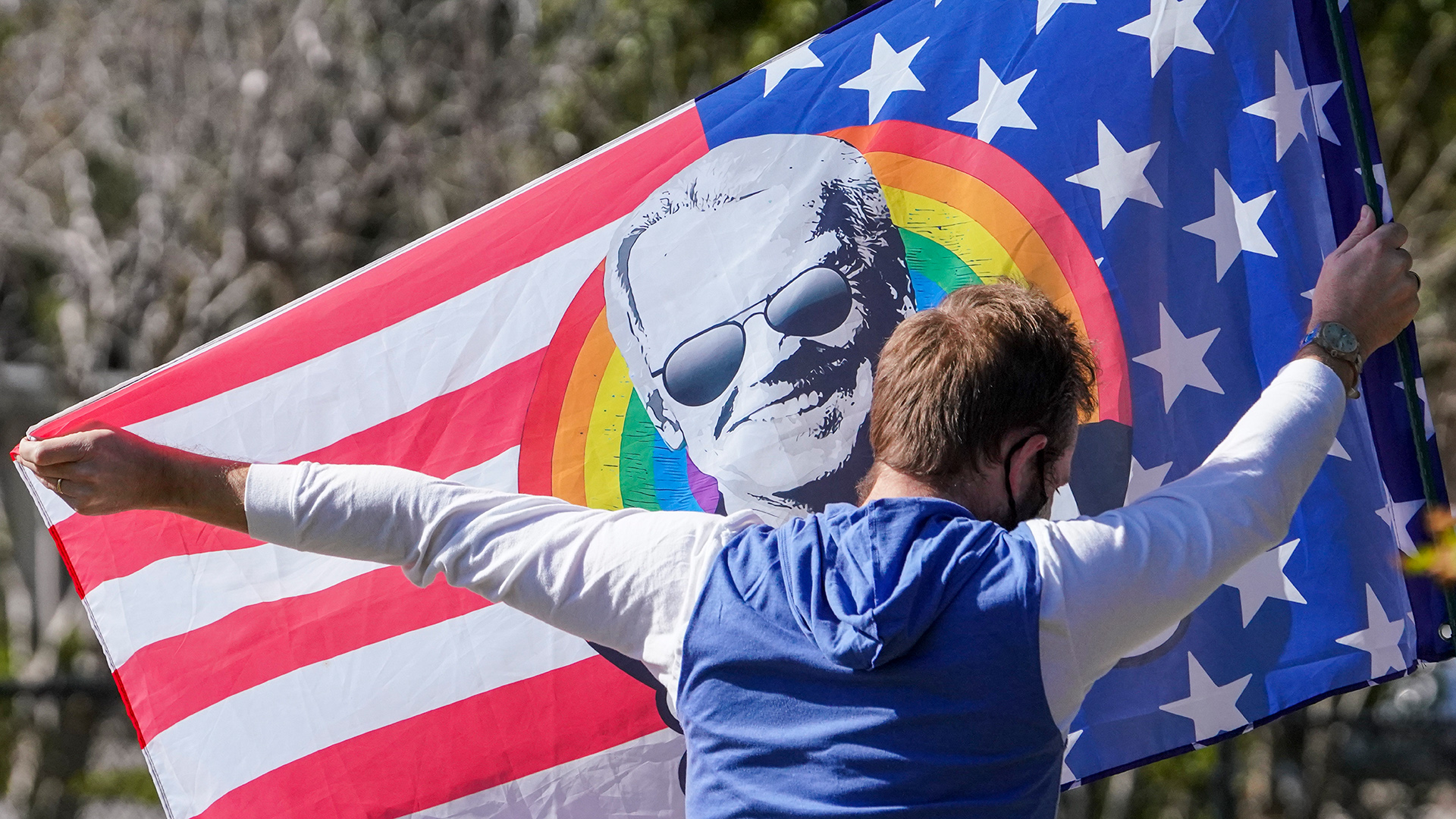 Ein Biden-Unterstützer hält eine Fahne seinem Konterfei vor "Stars and Stripes" und einem Regenbogen hoch.