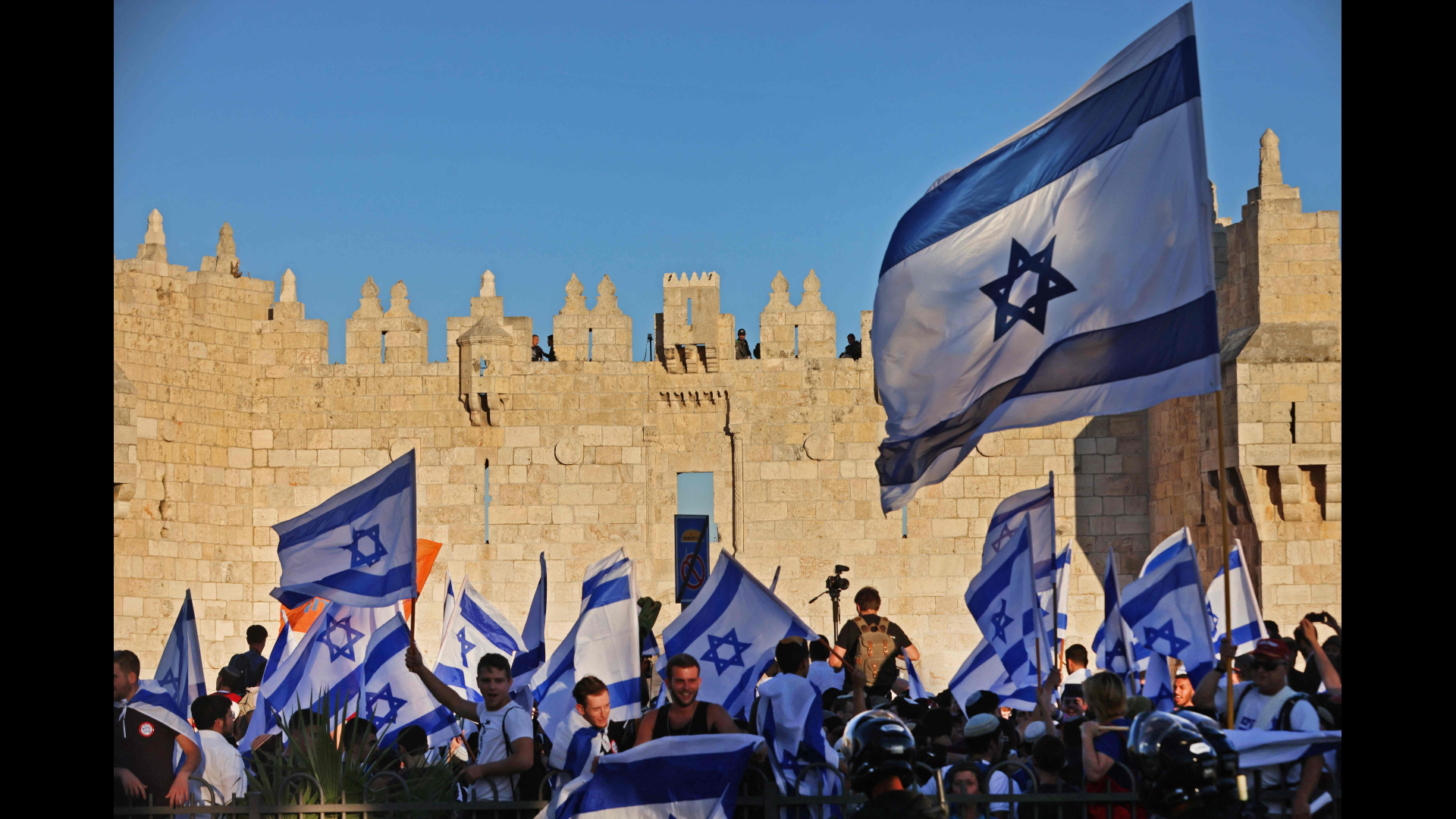 Teilnehmer des umstrittenen Flaggenmarschs durch Ostjerusalem schwenken israelische Flaggen.  | AFP