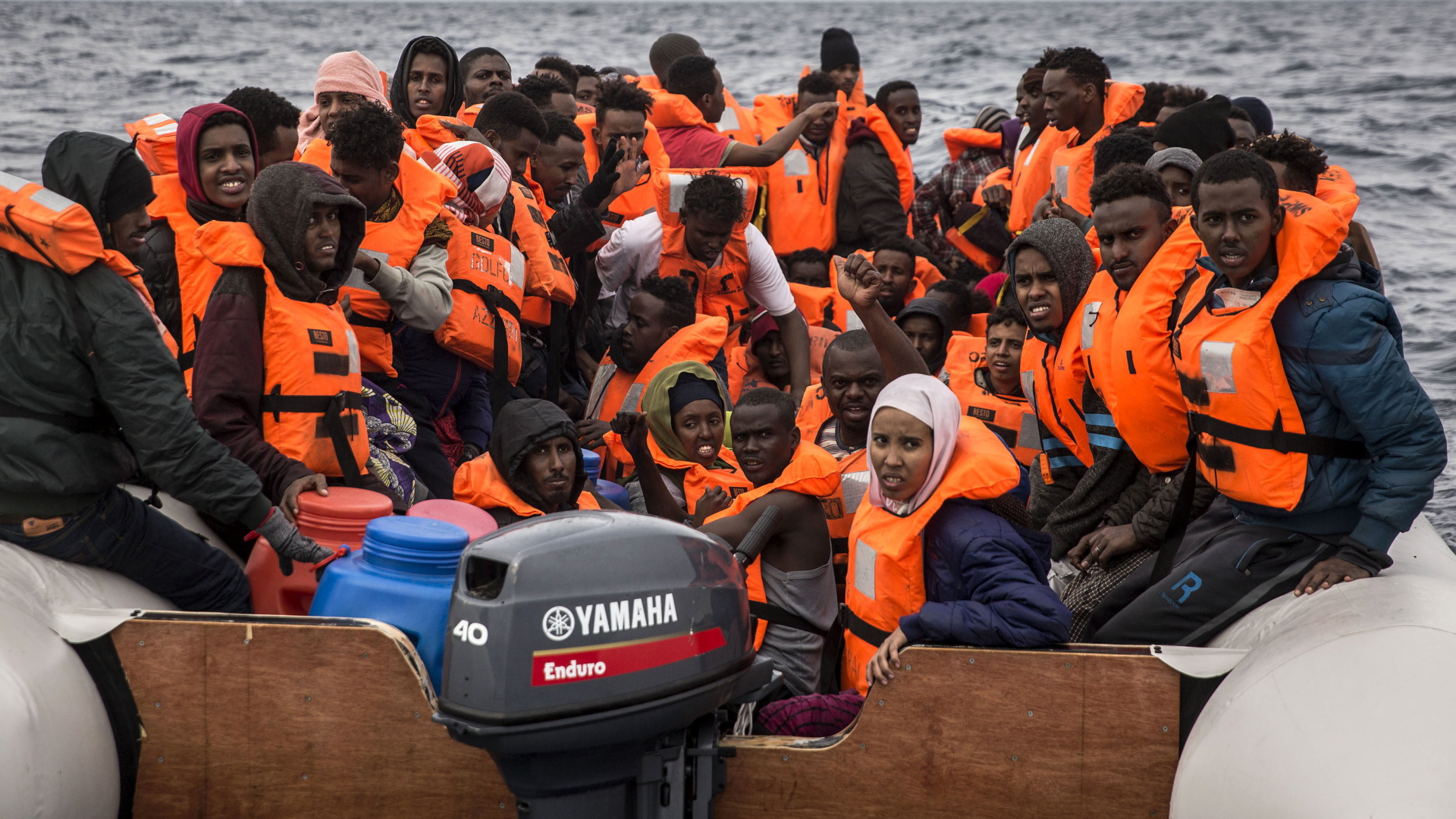 Flüchtlinge sitzen im Februar 2018 in orangen Rettungswesten in einem völlig überfüllten Schlauchboot auf dem Mittelmeer. | dpa