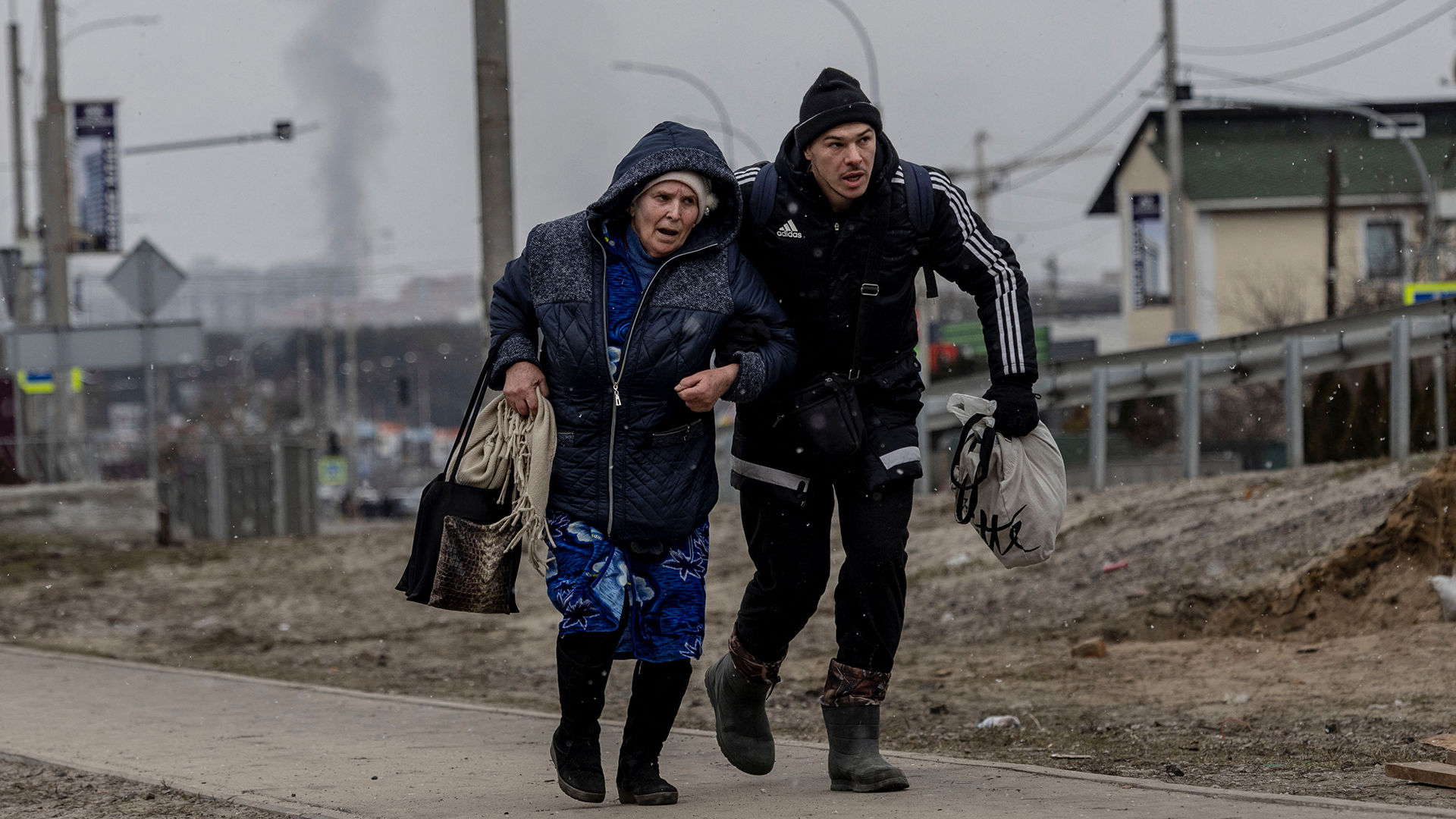 Ein Mann hilft einer älteren Frau auf dem einzigen Fluchtweg der Einheimischen in Deckung zu gehen, während russische Truppen in Richtung der Hauptstadt Irpin bei Kiew vorrücken | REUTERS