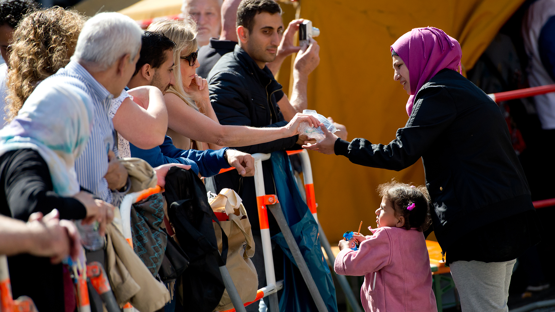 Eine Frau gibt einem Flüchtlingskind und seiner Mutter, welche zuvor mit einem Zug angekommen ist ein paar Spenden. | picture alliance / dpa
