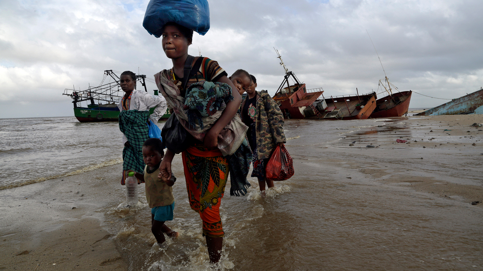Vertriebene Familien waten bei ihrer Ankunft in Beira durchs Wasser. | dpa
