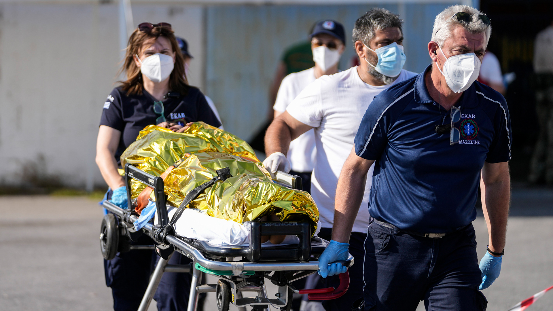Sanitäter tragen einen verletzten Überlebenden eines Schiffsunglücks zu einem Krankenwagen im Hafen der Stadt Kalamata.