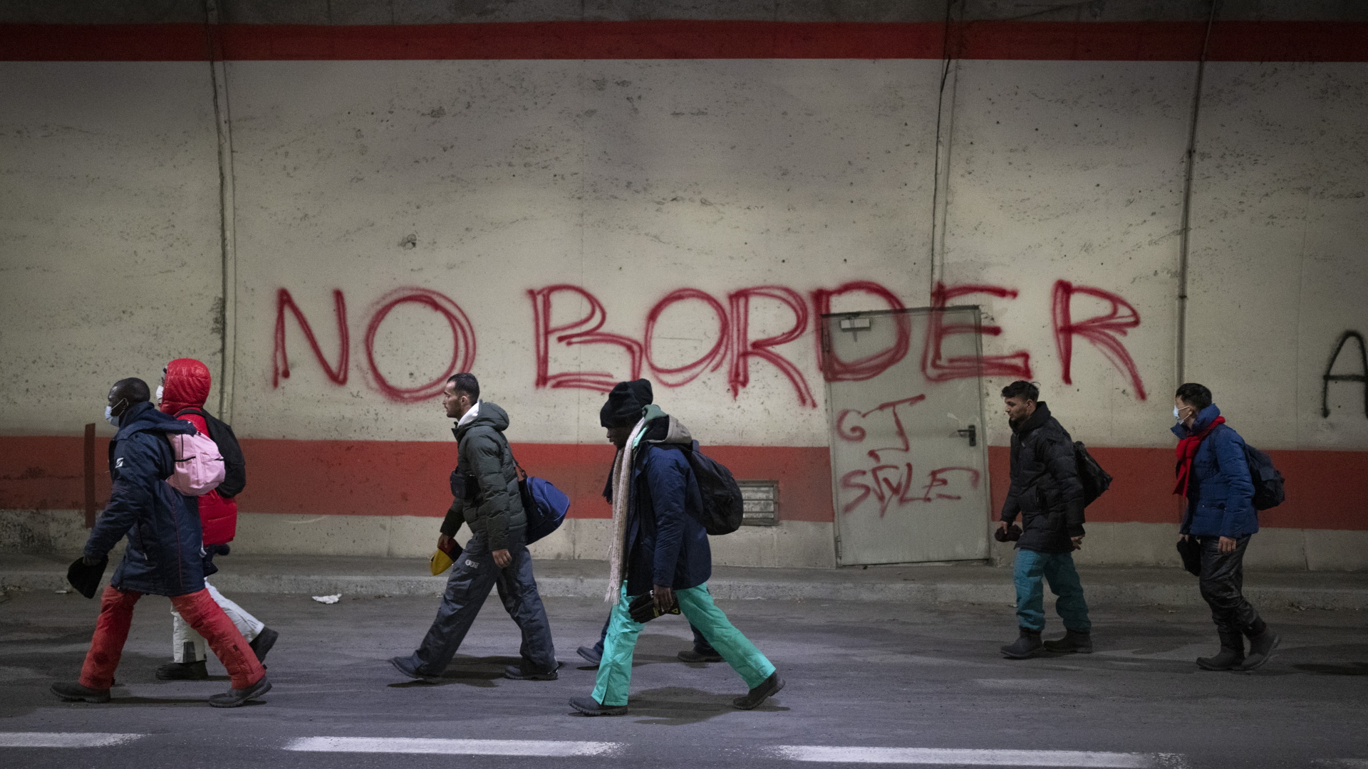Migranten, die auf dem Weg von Italien nach Frankreich sind, gehen an einem Graffiti mit der Aufschrift "No Border" vorbei  | dpa