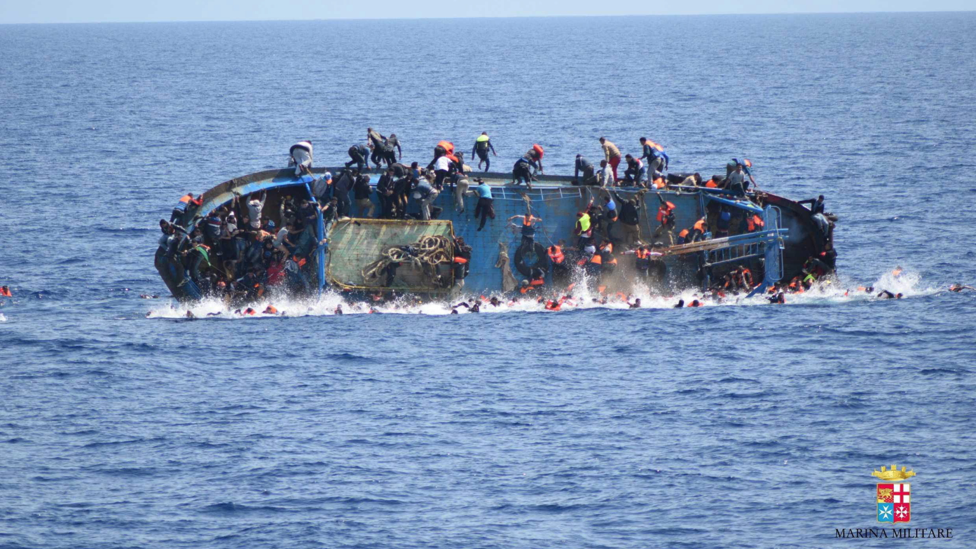 Flüchtlinge springen in der Nähe von Sizilien von einem kenternden Boot. Dieses Foto wurde im Mai von der italienischen Marine veröffentlicht. | dpa