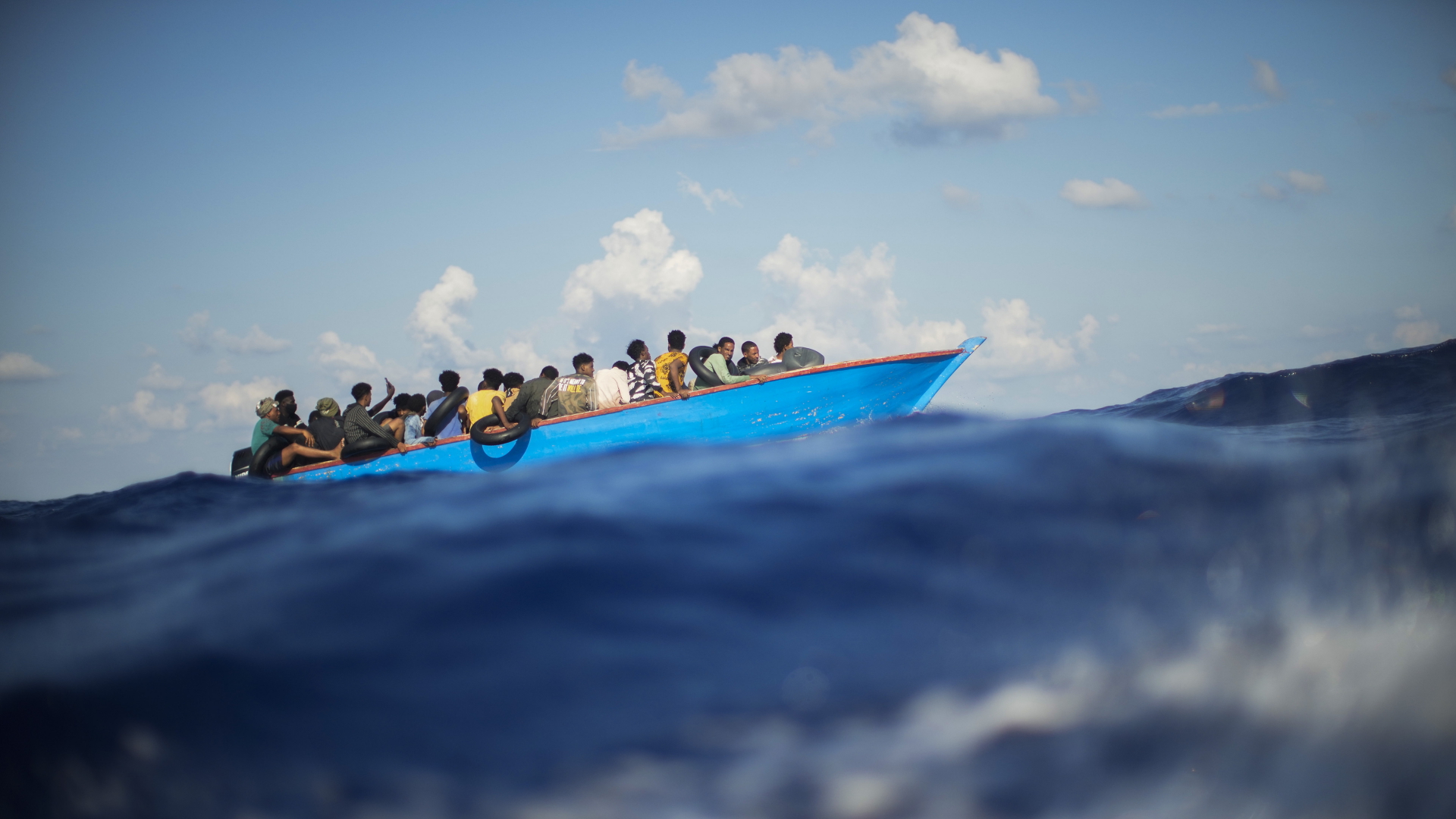 Migranten in einem Holzboot im August auf dem Mittelmeer. | dpa