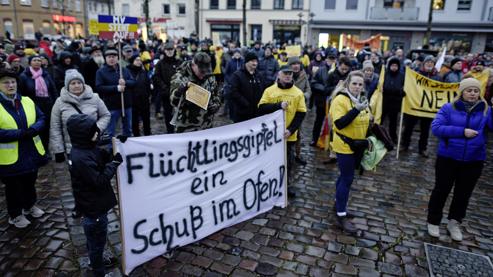 Menschen demonstrieren mit einem Banner mit der Aufschrift "Flüchtlingsgipfel - ein Schuss im Ofen" gegen eine geplante Flüchtlingsunterkunft in Nordwestmecklenburg. | dpa
