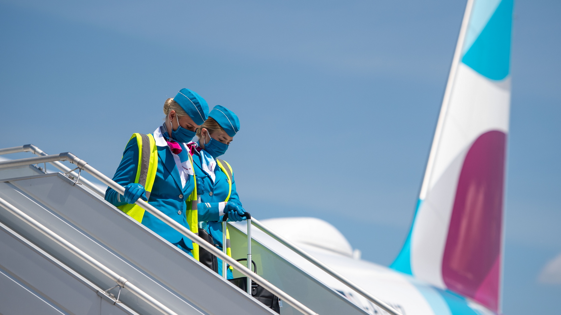 Zwei Flugbegleiterinnen mit Mund-Nasen-Schutz verlassen nach einem Pressetermin in Köln ein Flugzeug von Eurowings. | dpa