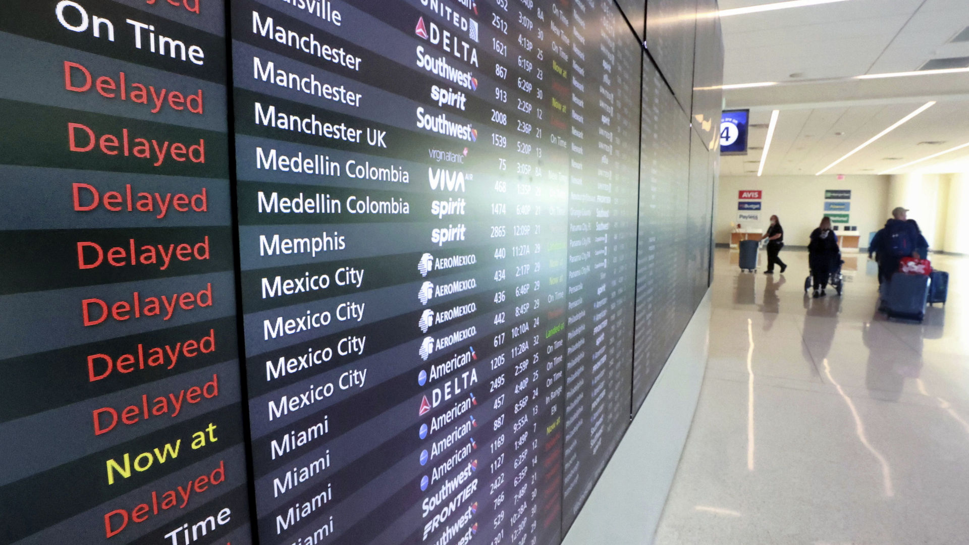 Reisende neben einer Anzeige mit verspäteten Flügen in Orlando, USA | AP