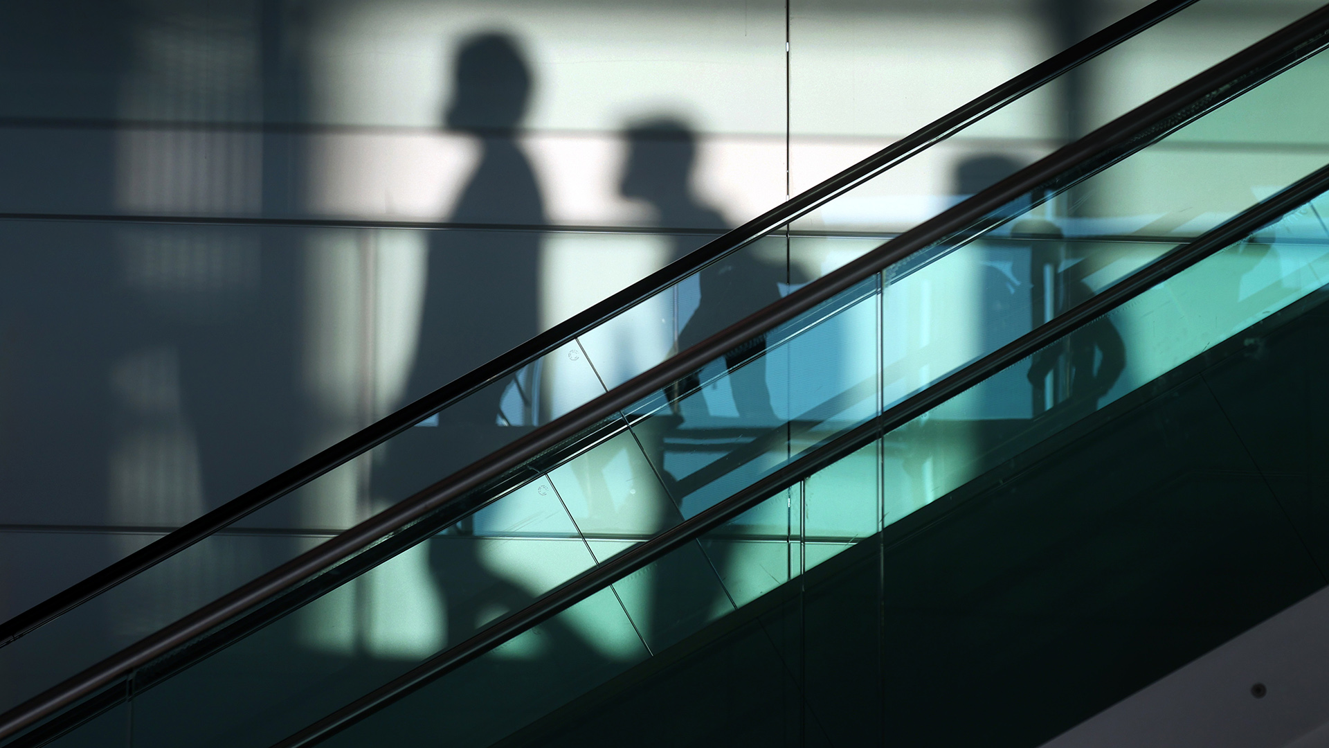 Schatten von Menschen hinter einer Rolltreppe | dpa
