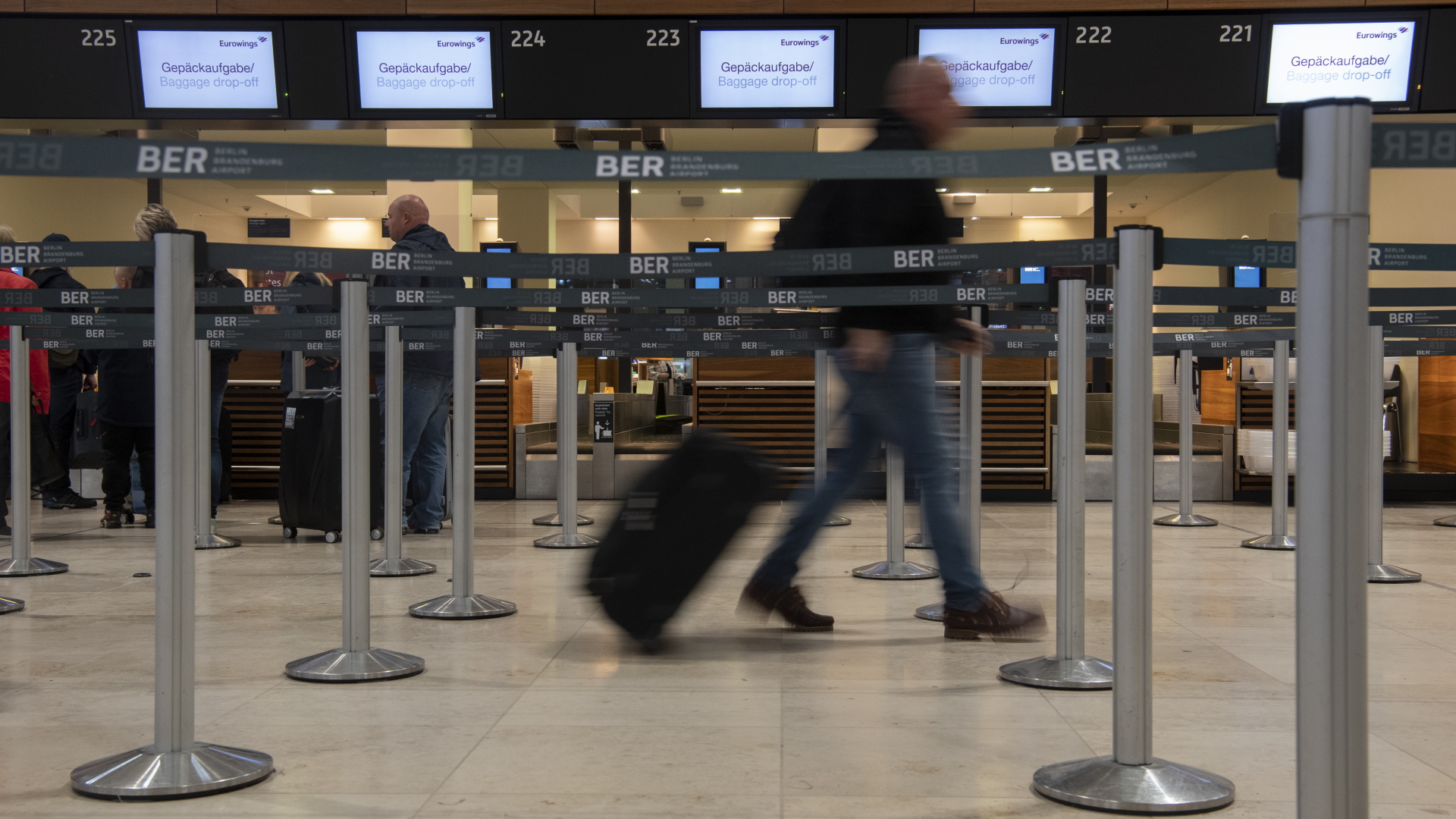 Ein Reisender geht mit einem Koffer zu einem Check-in-Schalter von Eurowings am Flughafen BER.  | dpa