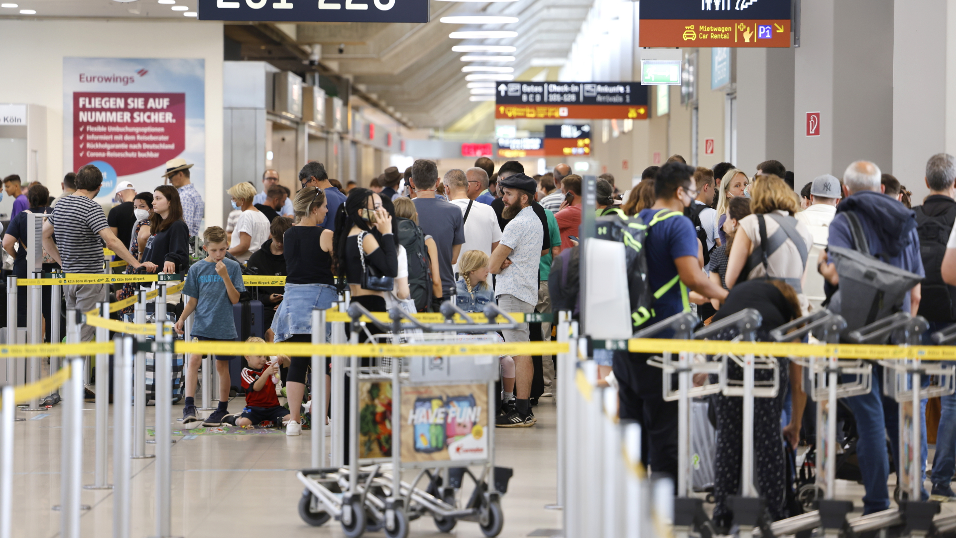 Menschen stehen am Check-In auf dem Kölner Flughafen in einer langen Warteschlange. | dpa
