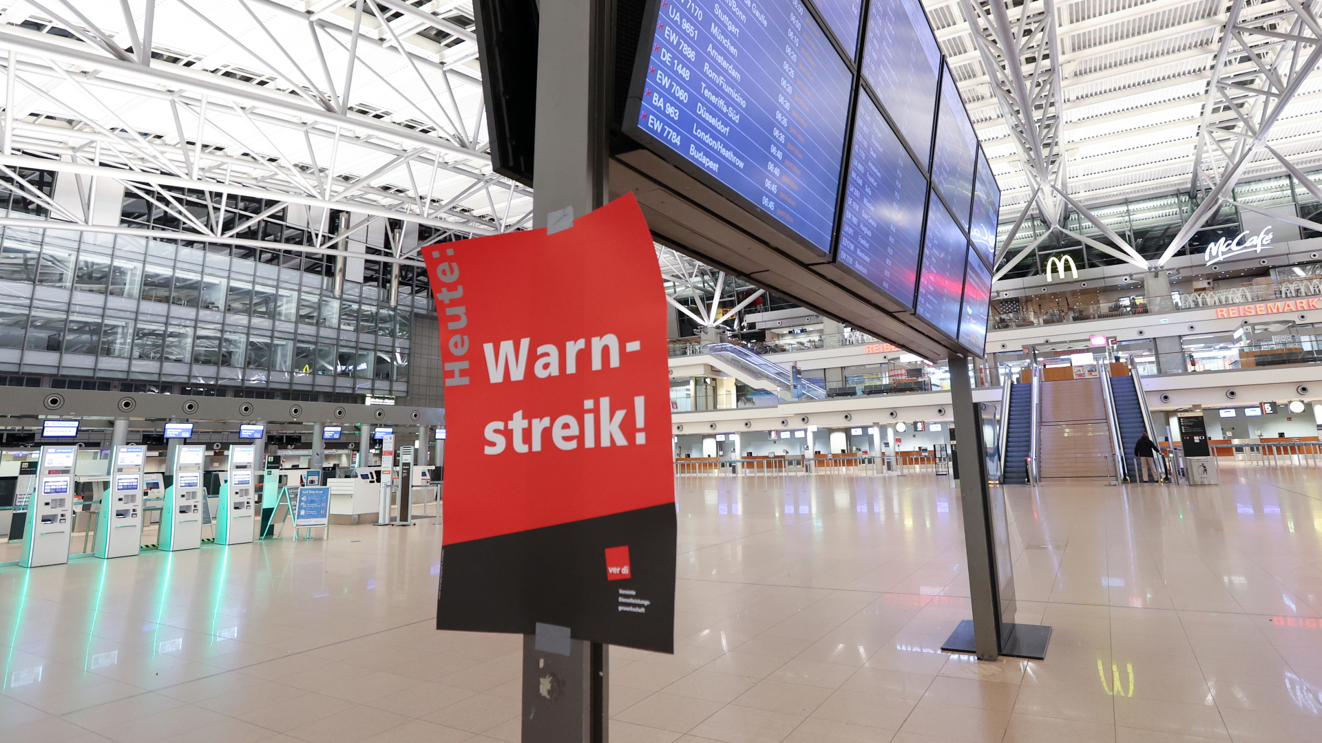 Ein Plakat mit der Aufschrift "Warnstreik!" klebt an der Anzeigetafel im leeren Terminal 1 im Hamburger Flughafen. | dpa
