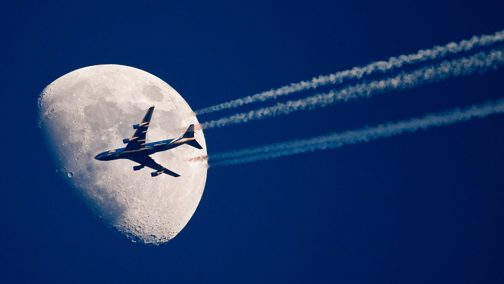 Ein Flugzeug am Himmel vor dem Mond | dpa