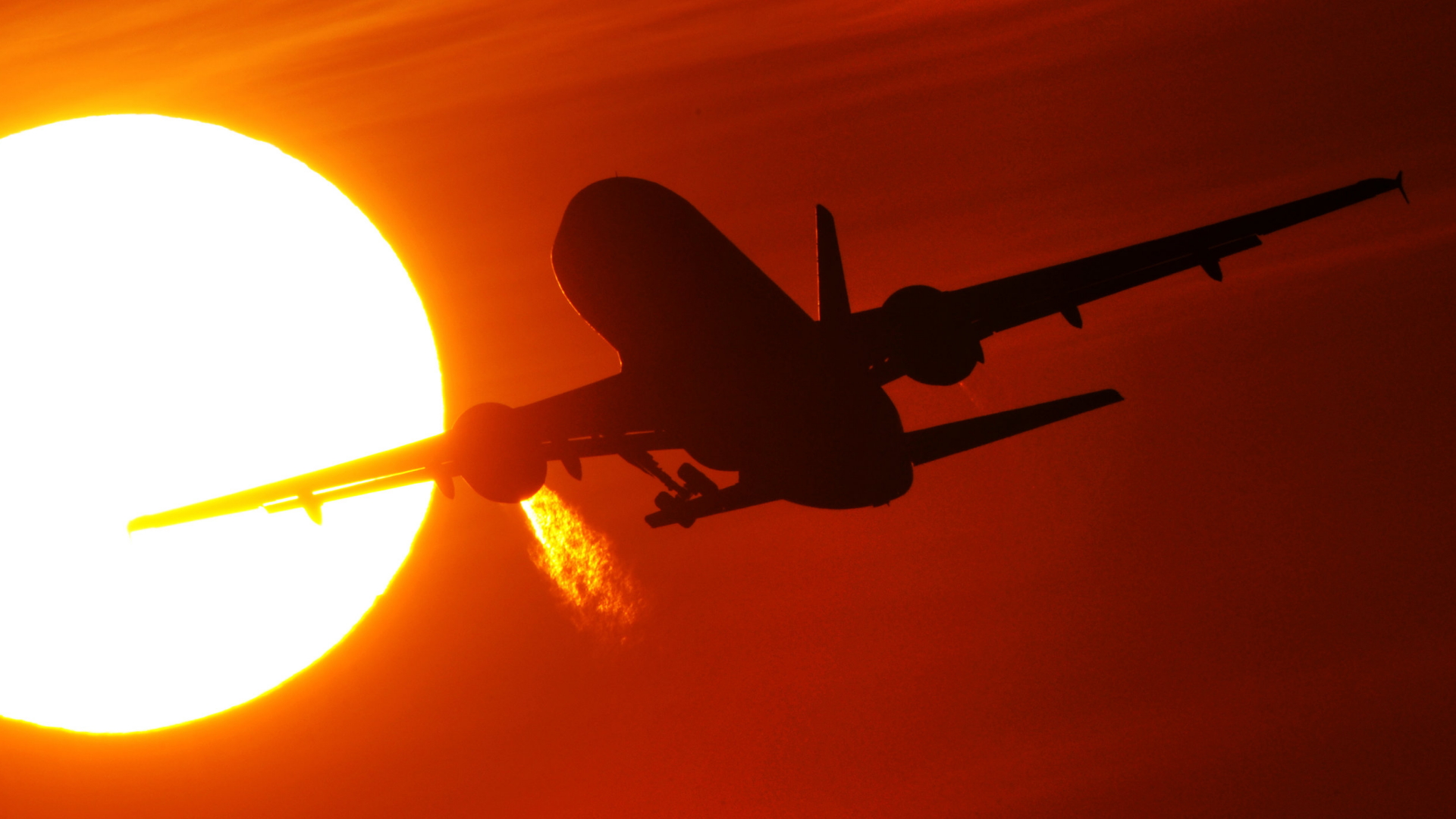 Ein Flugzeug startet am Flughafen Düsseldorf vor der untergehenden Sonne.  | dpa