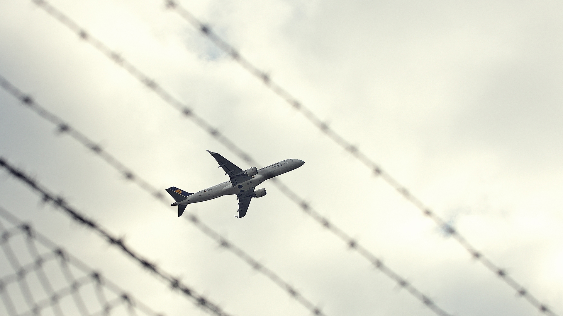Startendes Flugzeug durch einen Zaun fotografiert | picture alliance / Daniel Kubirs