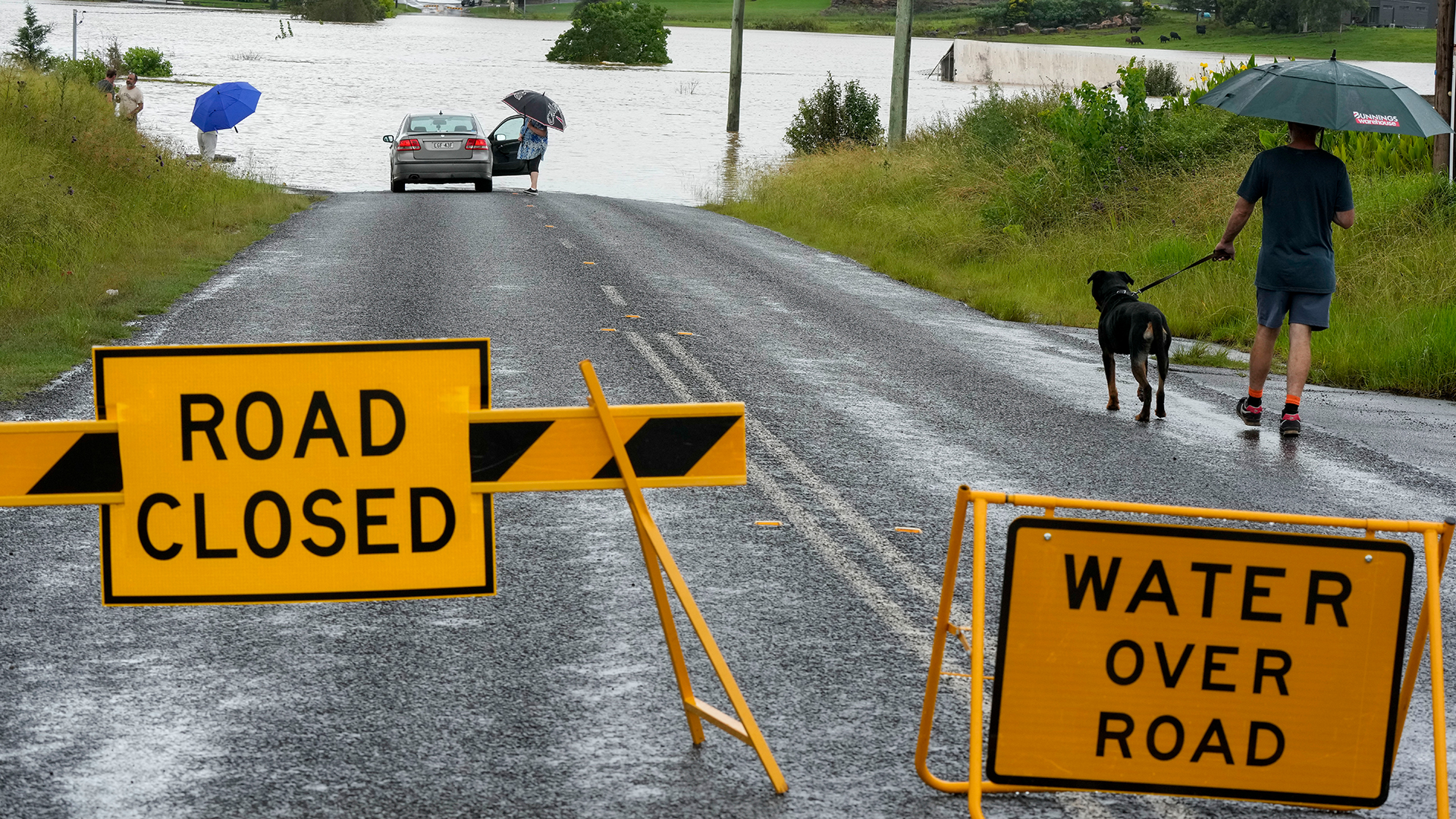 Anwohner blicken auf eine überschwemmte Straße in der Nähe von Windsor am Stadtrand von Sydney. | picture alliance/dpa/AP