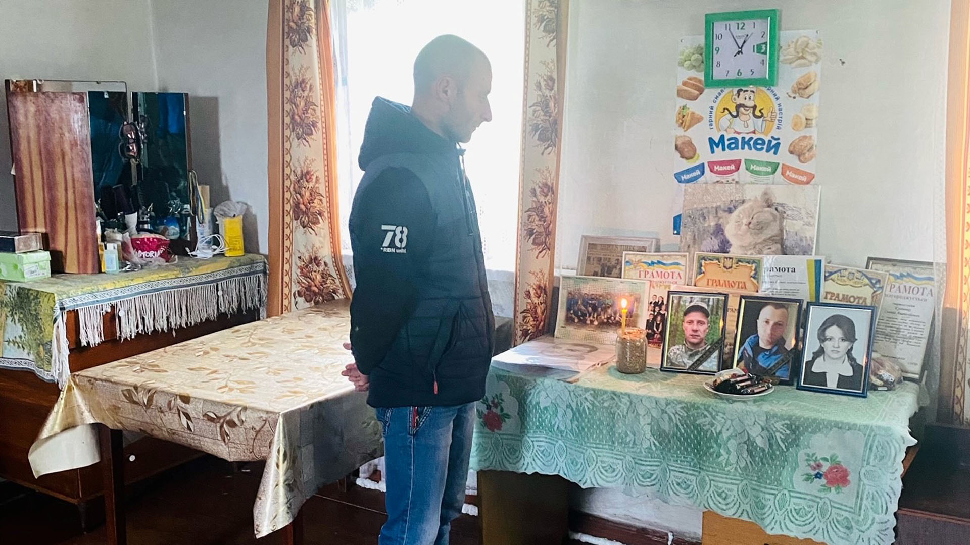 Mykola Kulischenko steht an einem Tisch mit Bilder seiner getöteten Brüder.