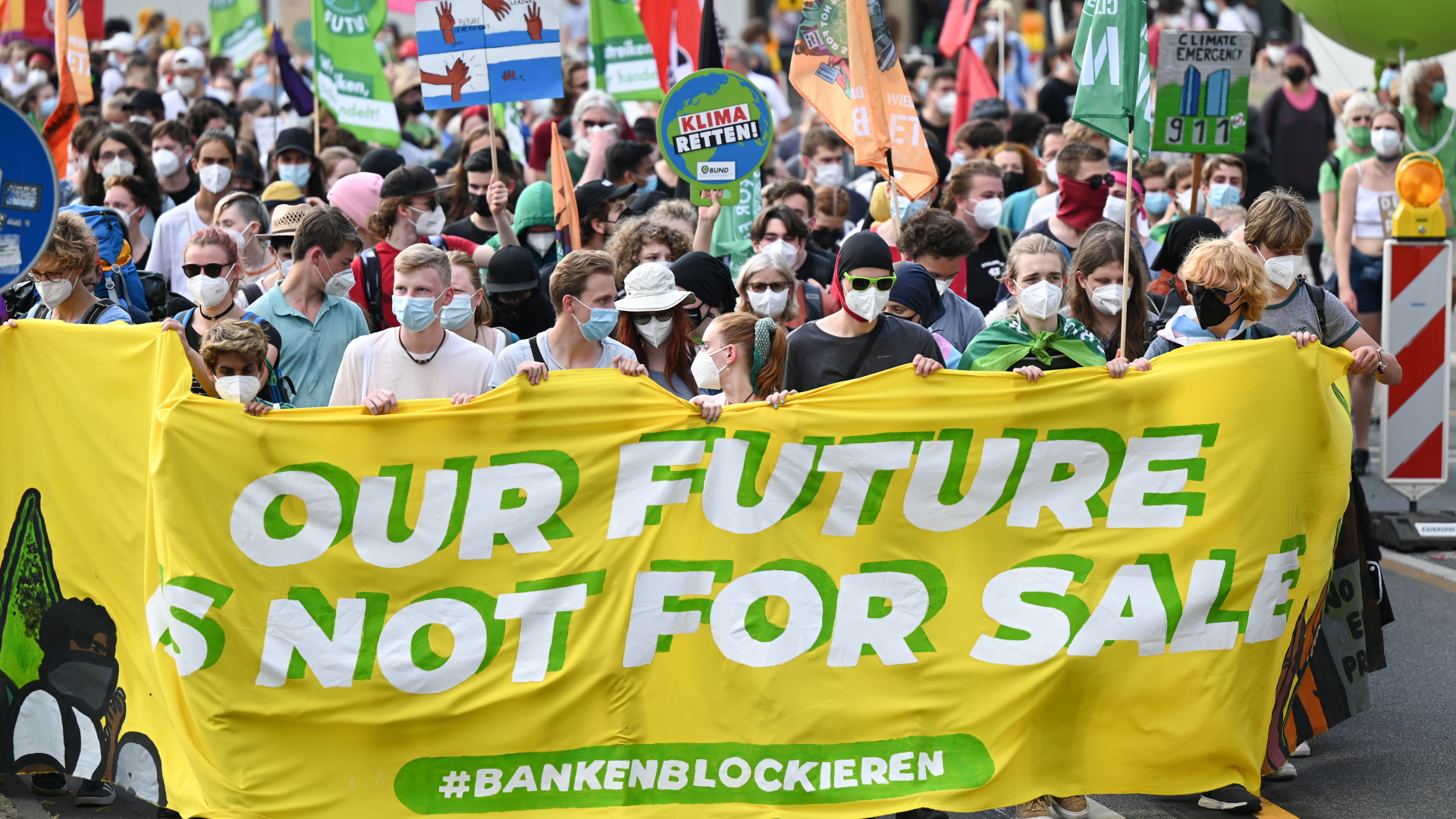 Demonstranten tragen beim zentralen Klimastreik von Fridays for Future während des Demonstrationszuges durch das Bankenviertel ein Plakat mit der Aufschrift "Our future is not for sale". | dpa