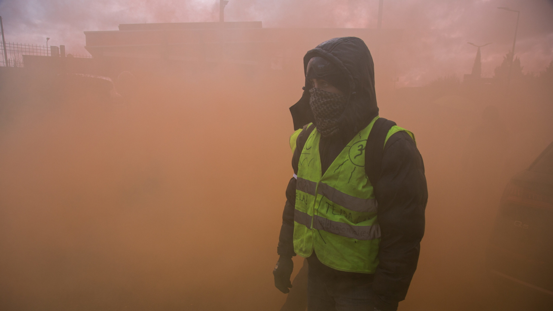 Ein vermummter Demonstrant der "Gelbwesten" steht in dichtem Rauch von Rauchgranaten. | dpa