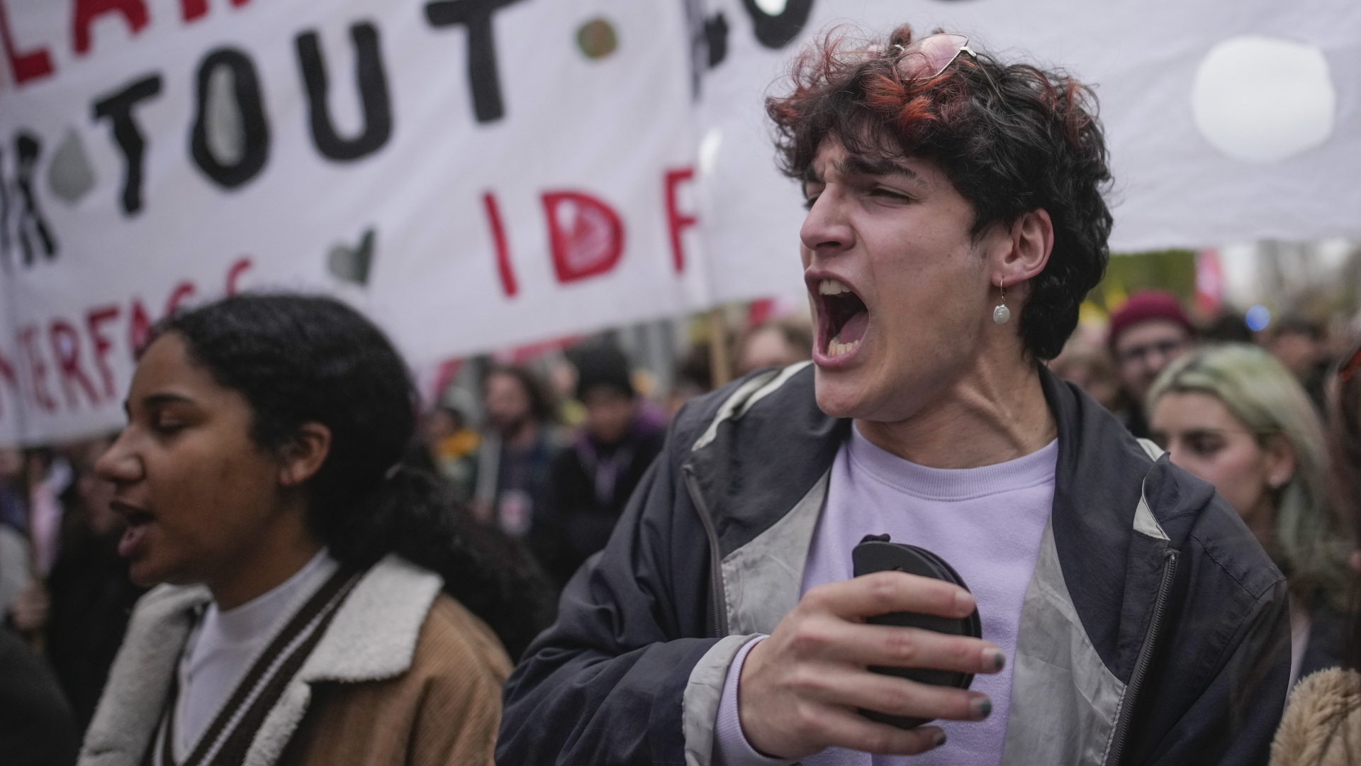 Eine junge Frau und ein junger Mann rufen Parolen auf einer Demonstration in Paris.