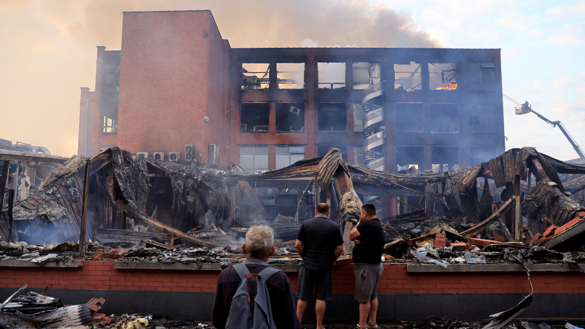 In Roubaix stehen Leute vor einem ausgebrannten Bürogebäude eines Verkehrsunternehmens, das bei schweren Ausschreitungen in Brand gesetzt worden war.