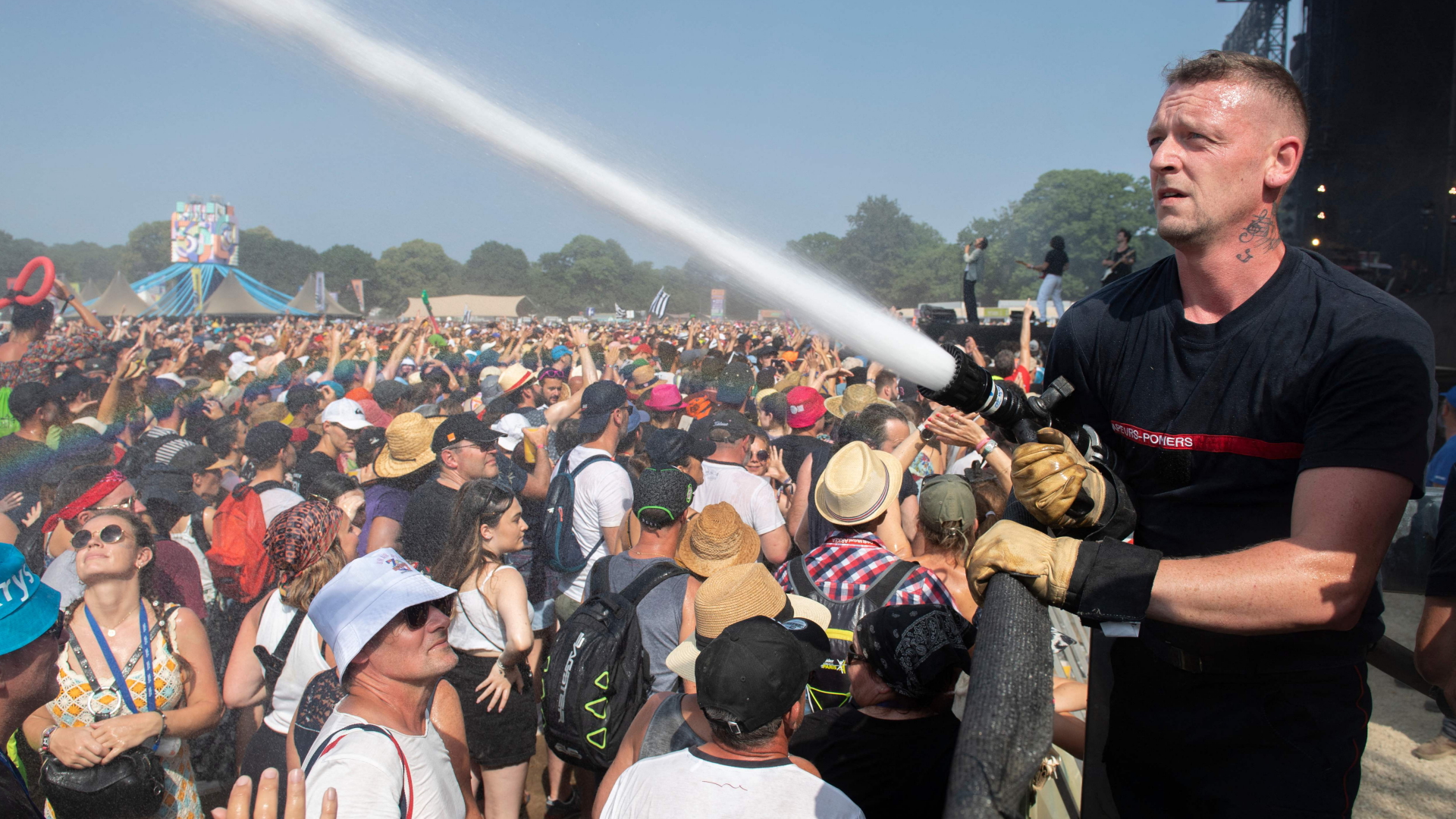 Ein Feuerwehrmann spritzt Wasser Richtung Zuschauer bei einem Festival in Carhaix-Plouguer