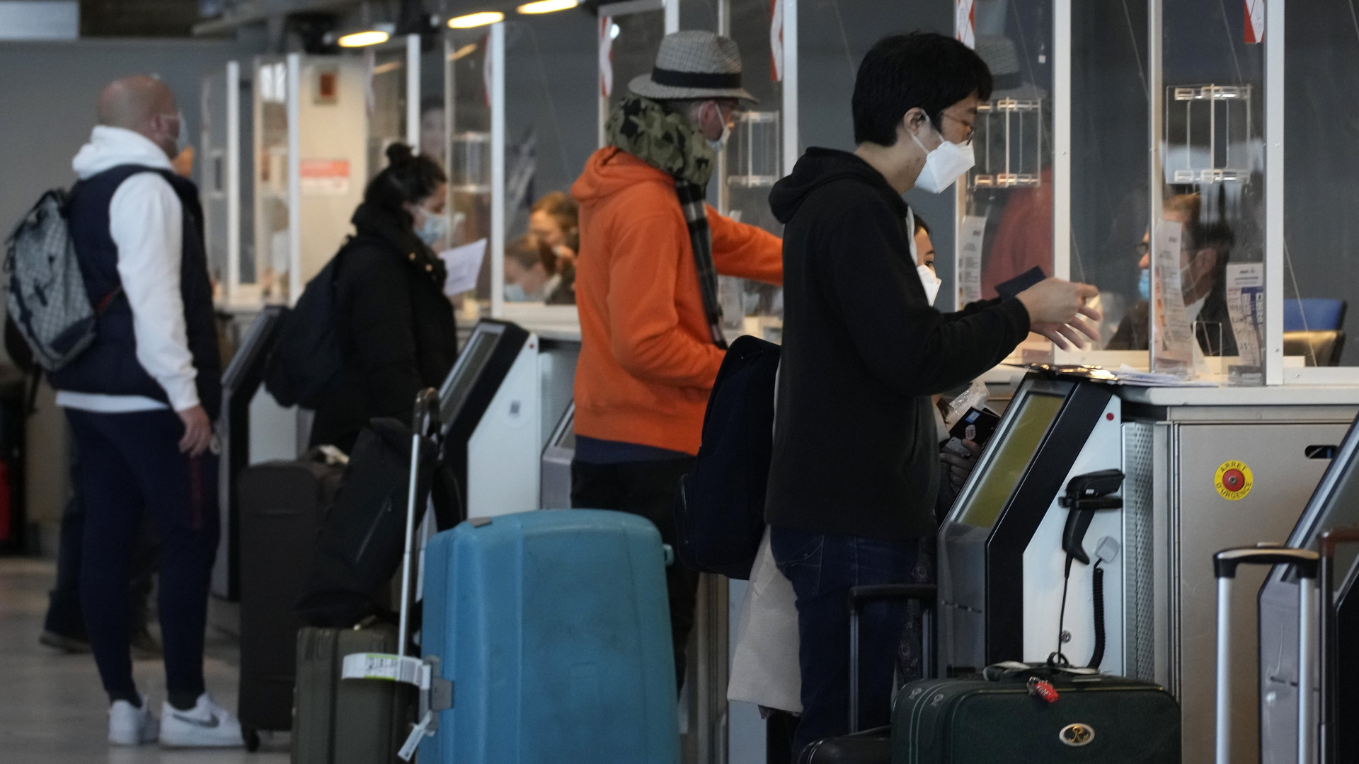 Reisende mit Corona-Schutzmasken zeigen am Flughafen Charles de Gaulle in Paris ihre Dokumente vor. | AP