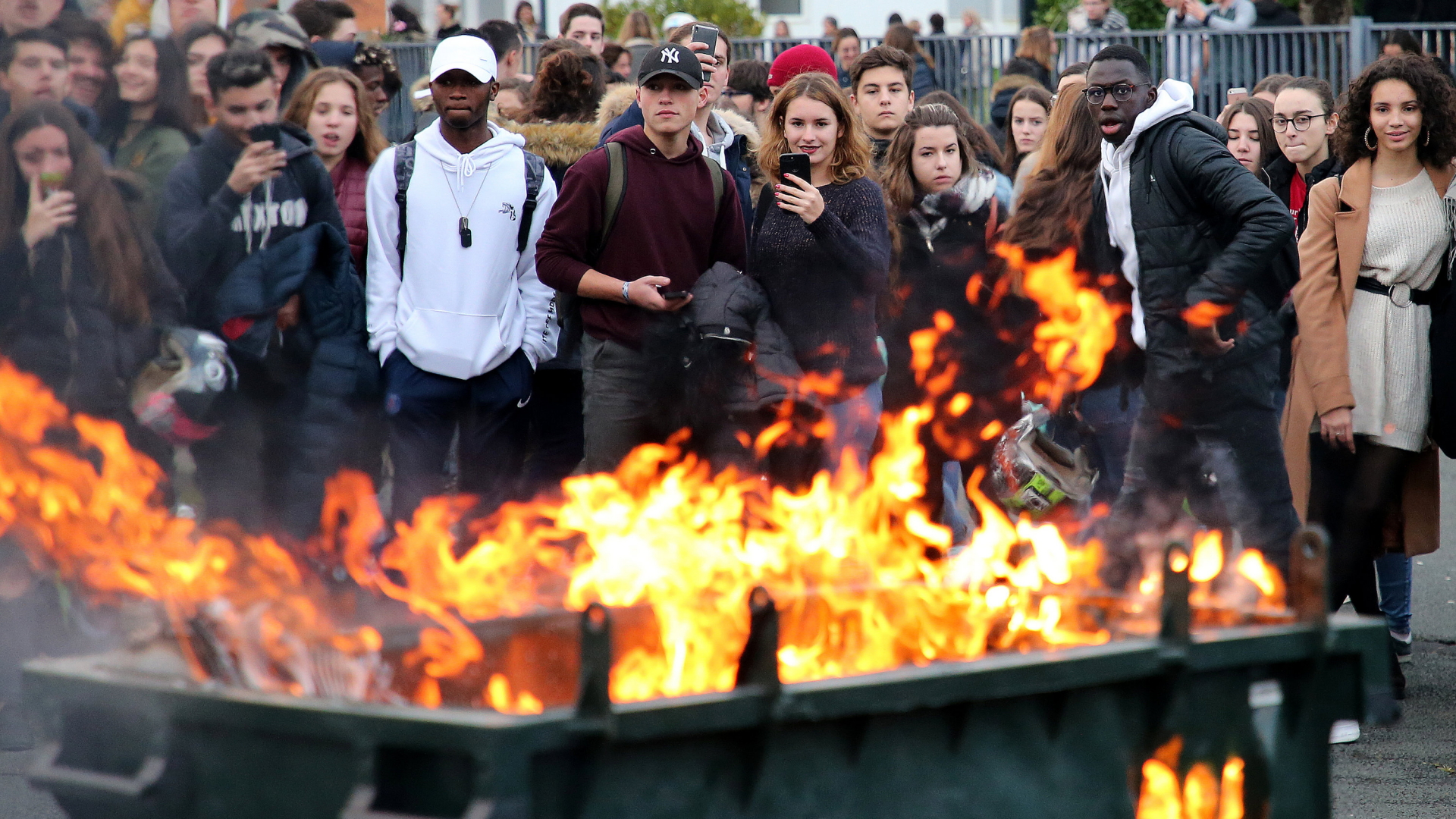 Im französischen Bayonne stehen Schüler, die sich an den Protesten gegen die Regierung beteiligen, vor einer brennenden Mülltonne. | Bildquelle: dpa