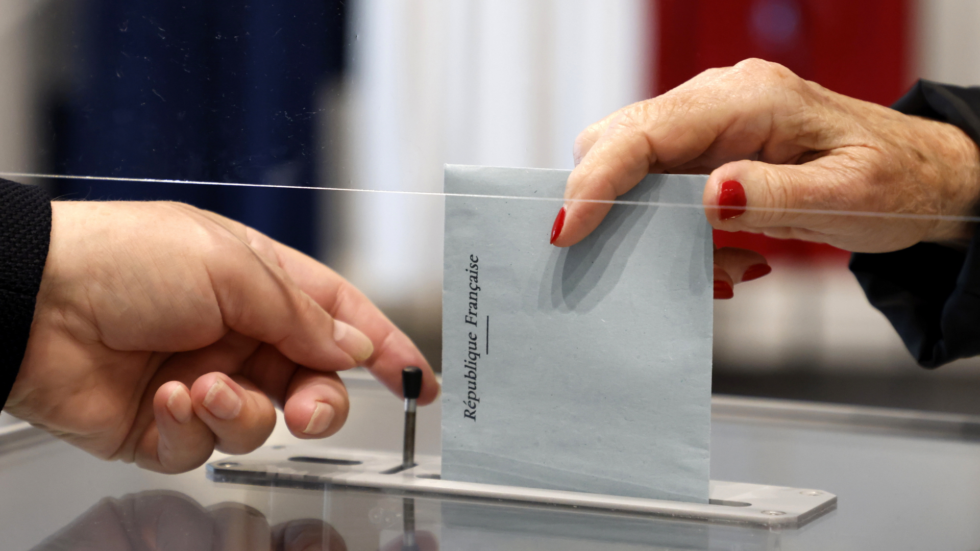 Eine Person wirft ihren Stimmzettel in einem Wahllokal in eine Wahlurne. | dpa
