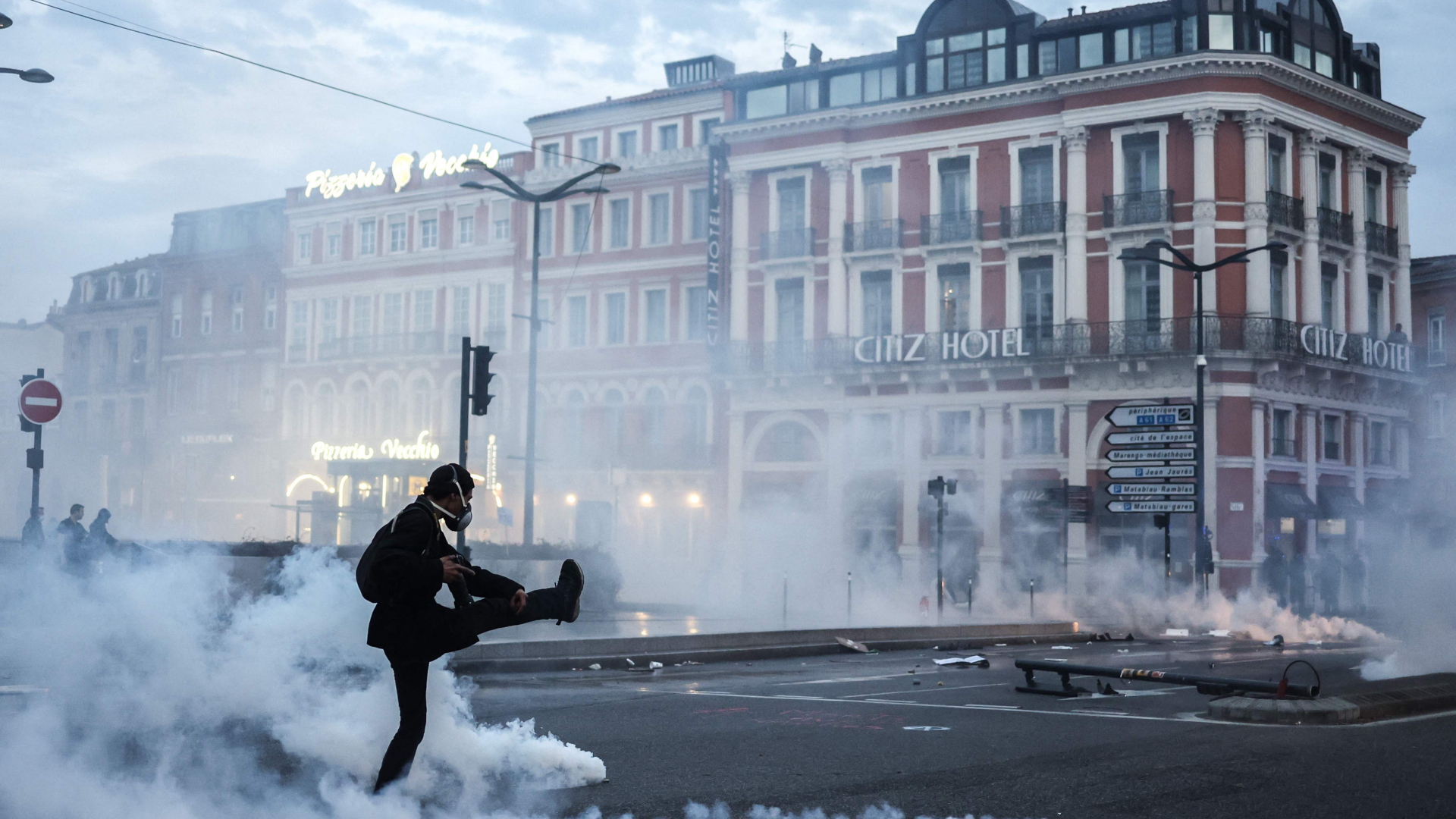 Ein Demonstrant mit Gasmaske tritt eine Tränengaskartusche auf einer Kreuzung in Toulouse weg. | AFP