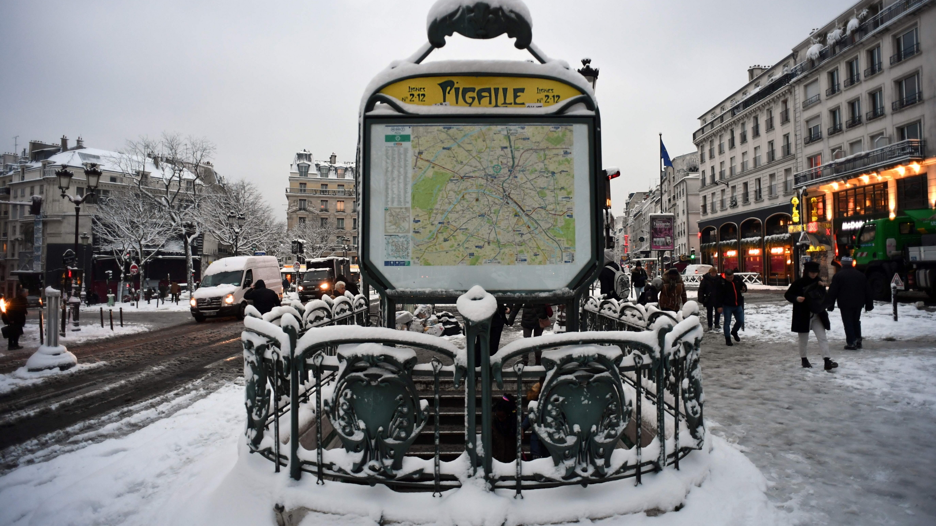 Passanten laufen im verschneiten Paris an einer Station der Metro vorbei. | AFP