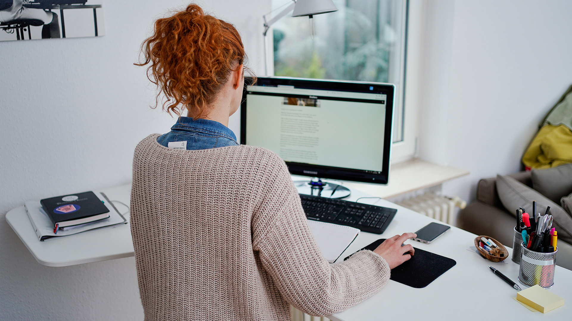 Eine Frau arbeitet vor einem Computer an einem Stehtisch.