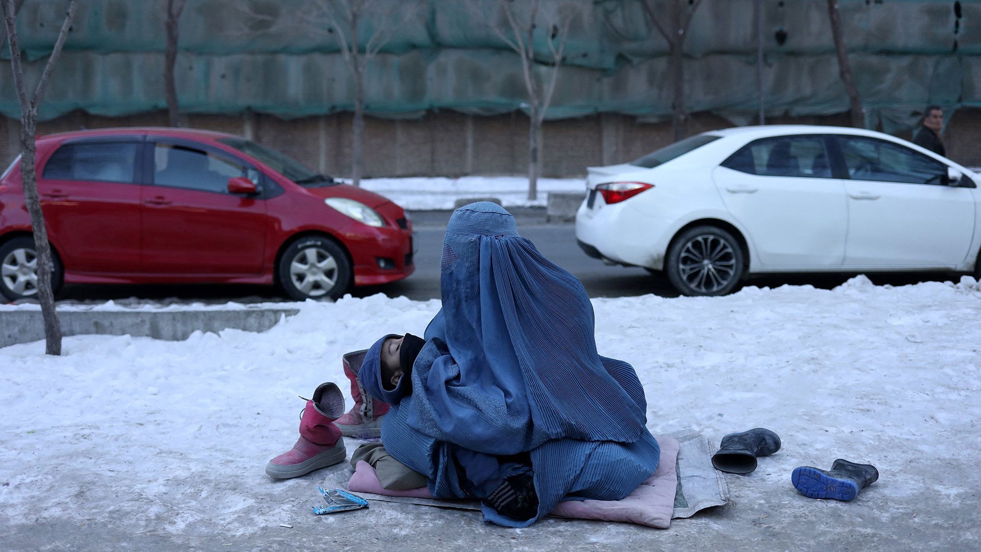 Eine afghanische Frau bettelt mit ihrem Kind auf einem schneebedeckten Bürgersteig in Kabul. | REUTERS