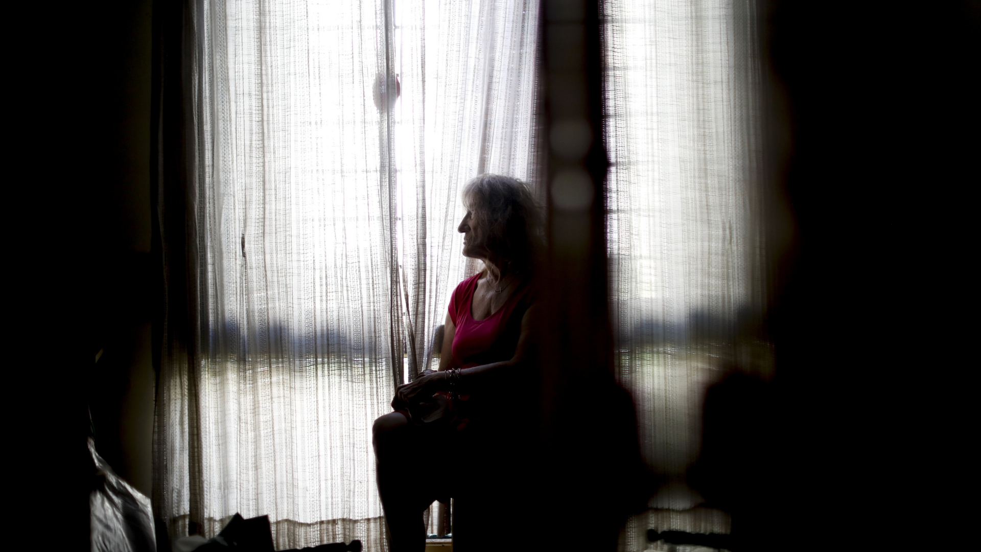 Eine Frau sitzt während der Coronavirus-Pandemie allein vor einem Zimmerfenster. | AP