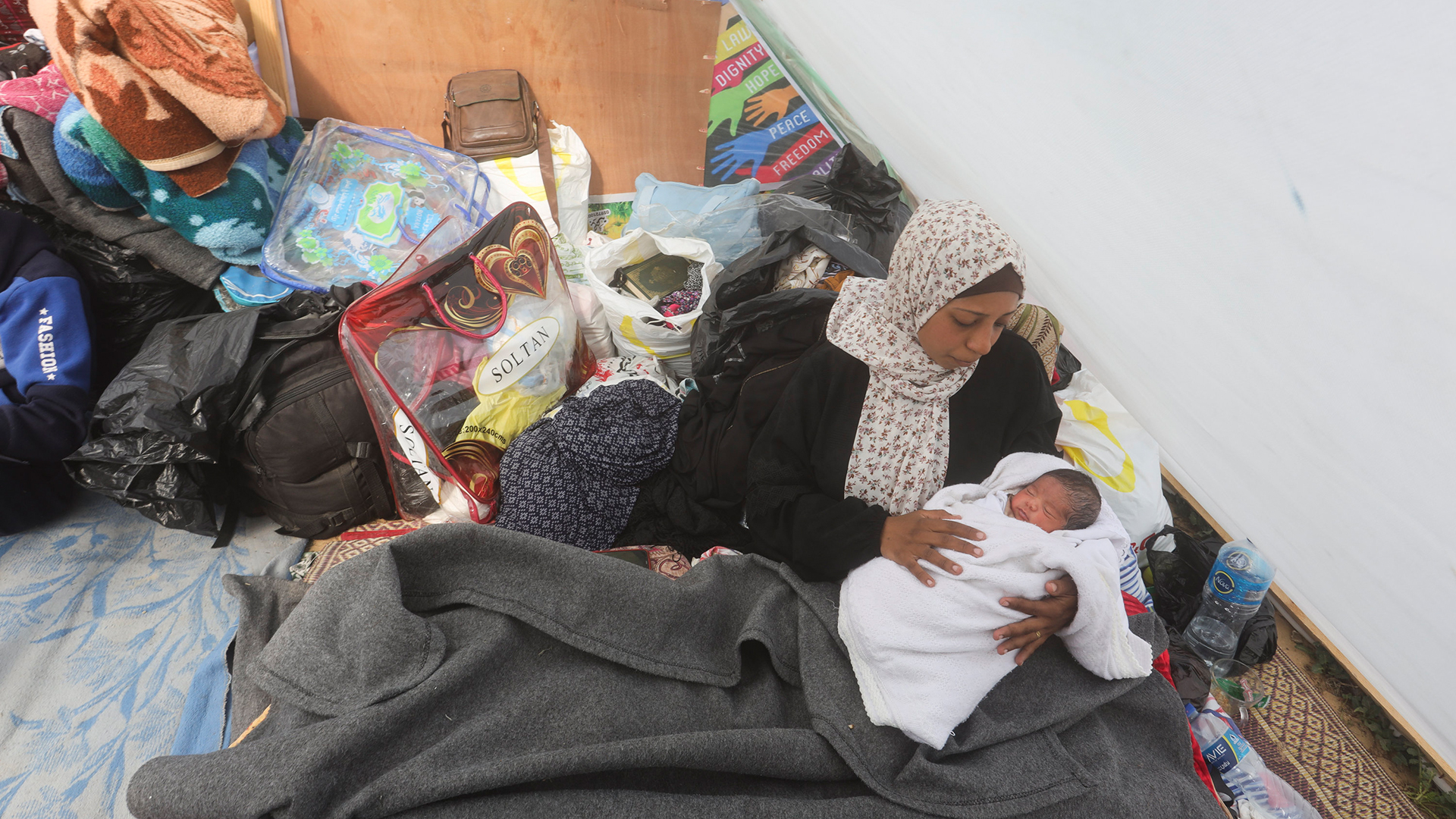 Eine Frau hält ihr Baby in einem Zelt in der Nähe des Kerem Shalom Übergangs in Rafah.