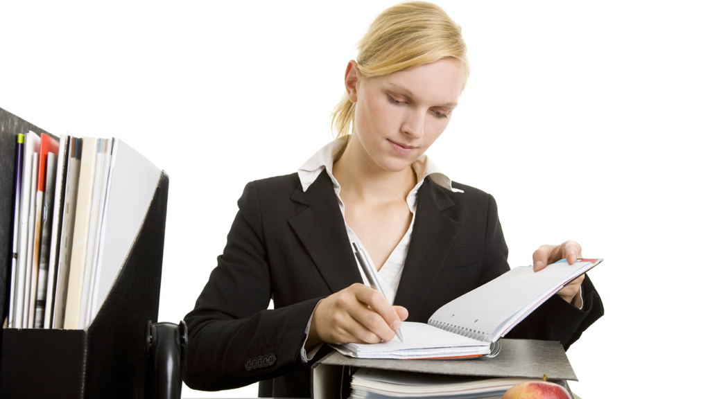 Blonde Managerin macht sich am Schreibtisch in ihrem Terminplaner Notizen | picture-alliance