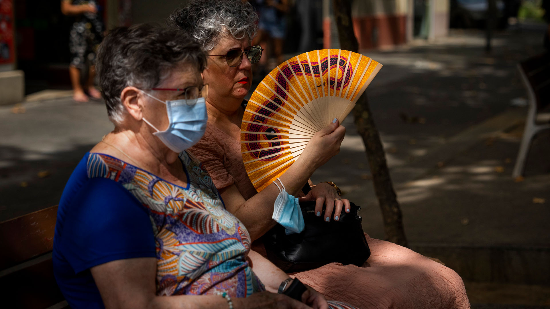 Zwei Frauen sitzen in Barcelona auf einer Parkbank. | AP