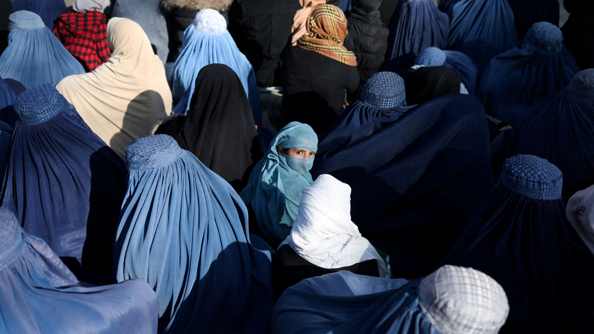 Ein Mädchen blickt aus einer Menschenmenge verschleierter Frauen in Kabul heraus. | REUTERS