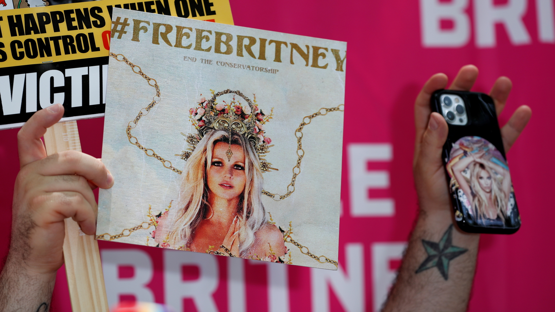 Ein Britney-Spears-Fan hält ein Plakat und eine Handyhülle mit ihrem Konterfei vor dem Gericht in Los Angeles in die Höhe (Foto vom 14.07.2021). | REUTERS