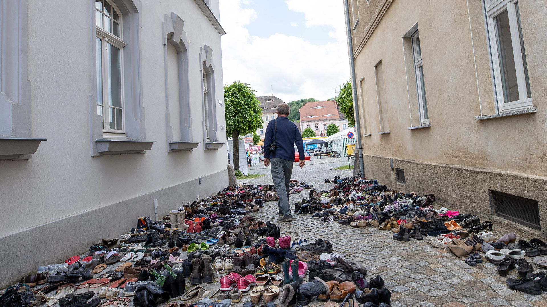 Ein Mann geht an vielen Schuhen beim Ostritzer Friedensfest vorbei.  | dpa