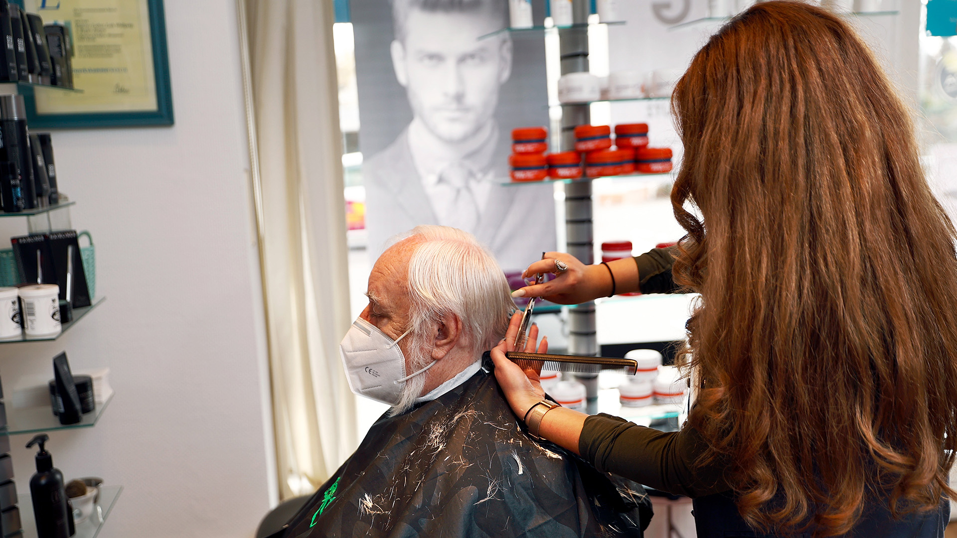 Eine Friseurin schneidet einem Kunden die Haare. | picture alliance/dpa