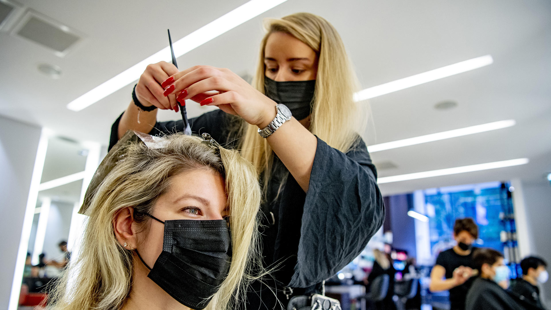 Eine Frisörin färbt einer Kundin die Haare | picture alliance / ROBIN UTRECHT