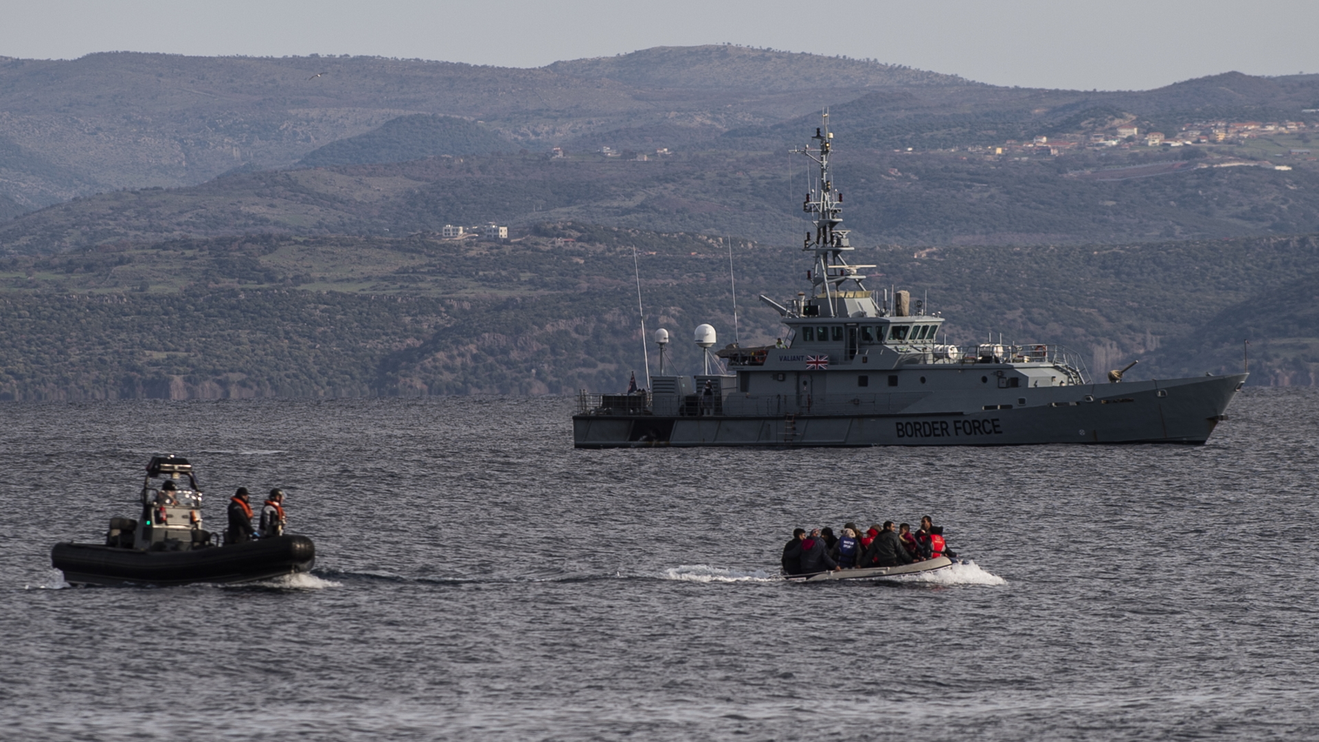 Ein Boot mit Flüchtlingen fährt auf die griechische Insel Lesbos vor, begleitet von einem Patrouillenboot der britischen Grenztruppen HMC Valiant, das Teil der Frontex Mission ist.